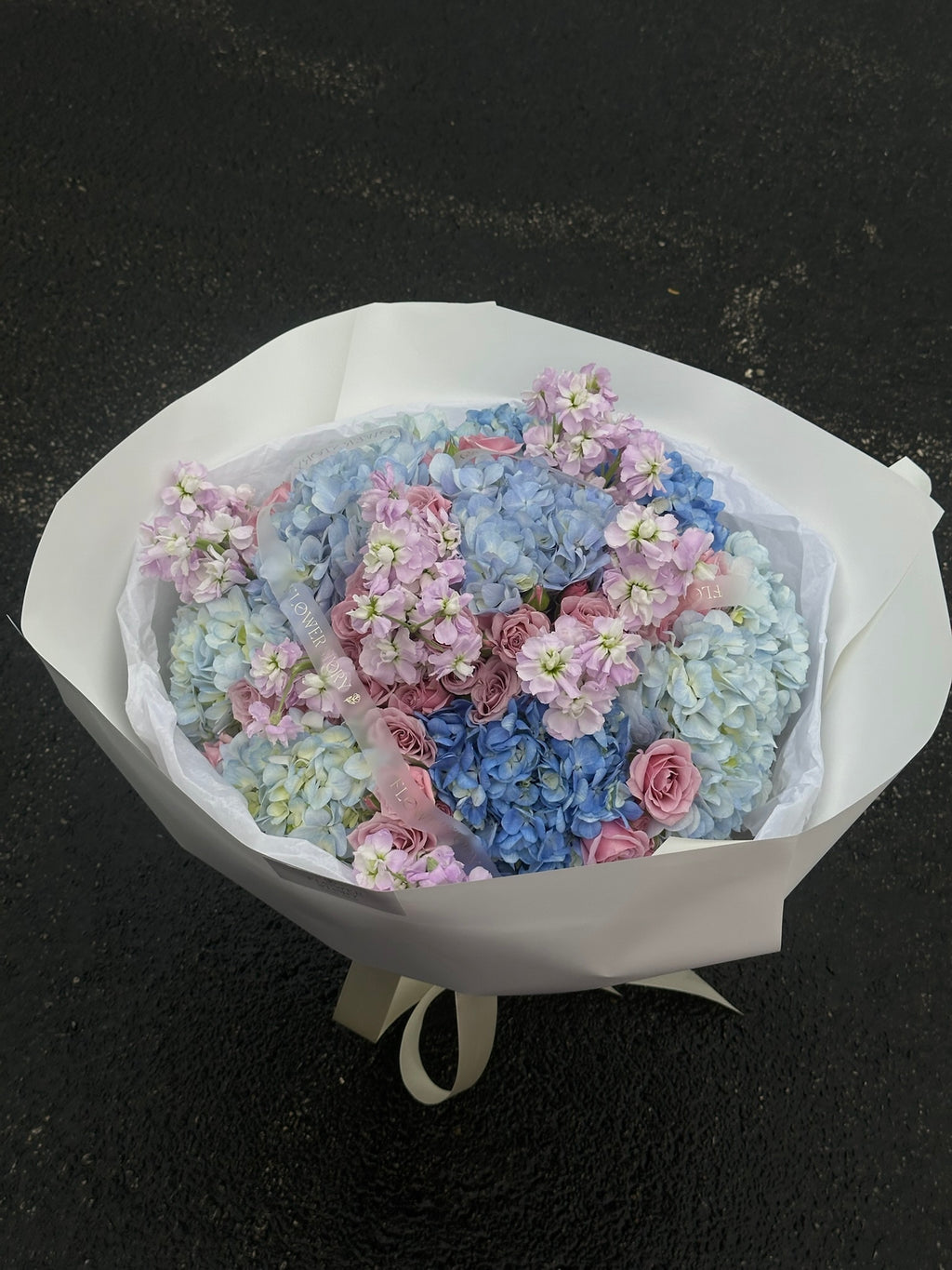 Mix bouquet of blue hydrangeas, purple spray roses & stock